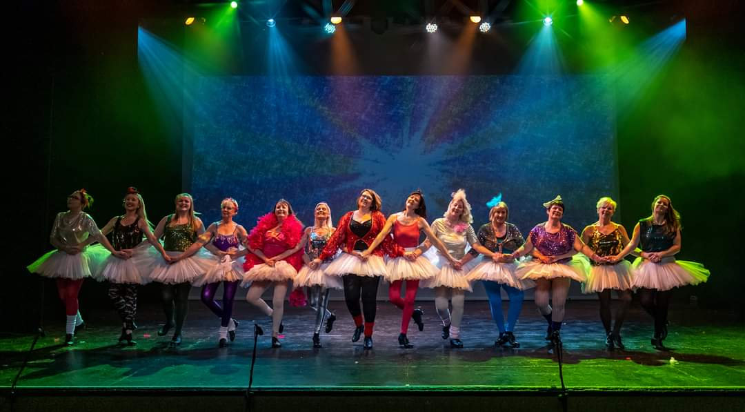 Junior dancers in red tutus lit in green on stage