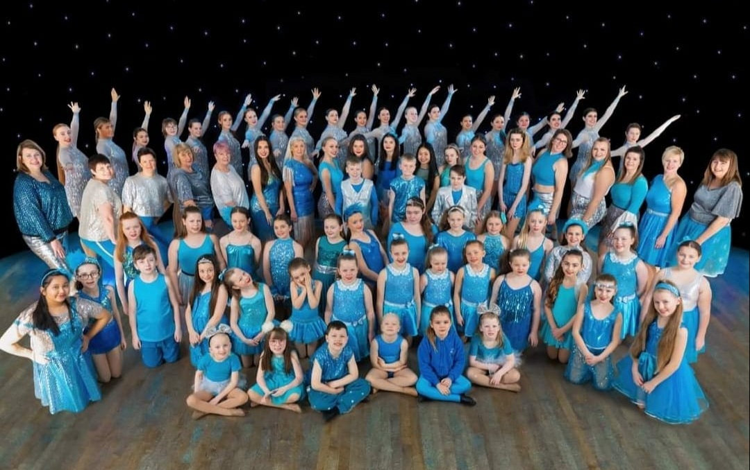 Large cast of Whittaker's students in teal costumes
