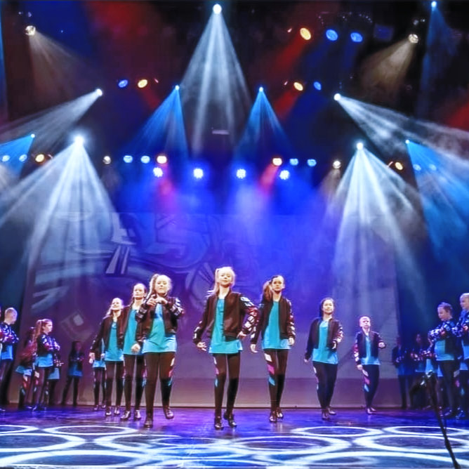 Irish dance team performing under blue stage lighting
